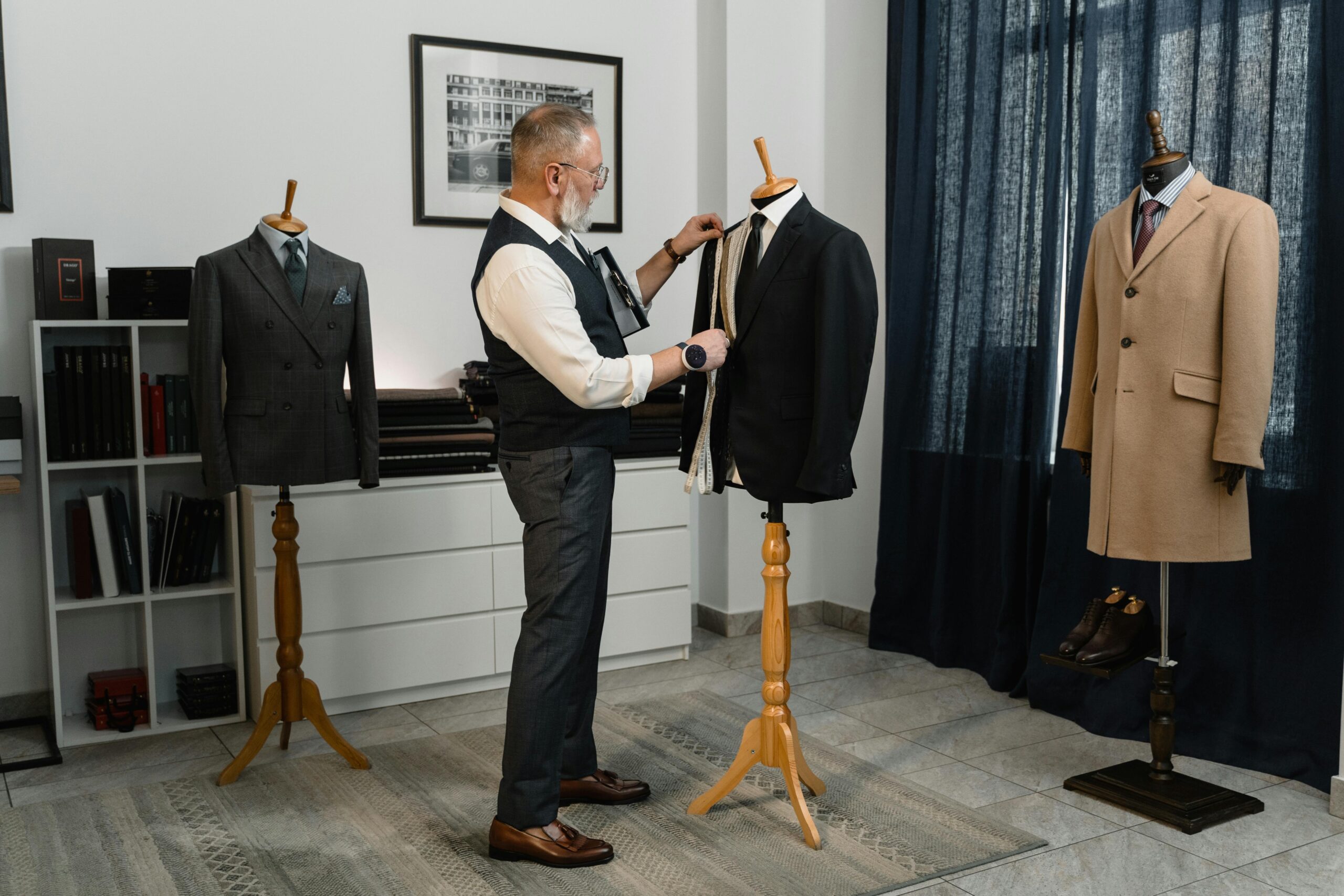 A tailor adjusting a suit on a mannequin in a professional fashion studio setting.
